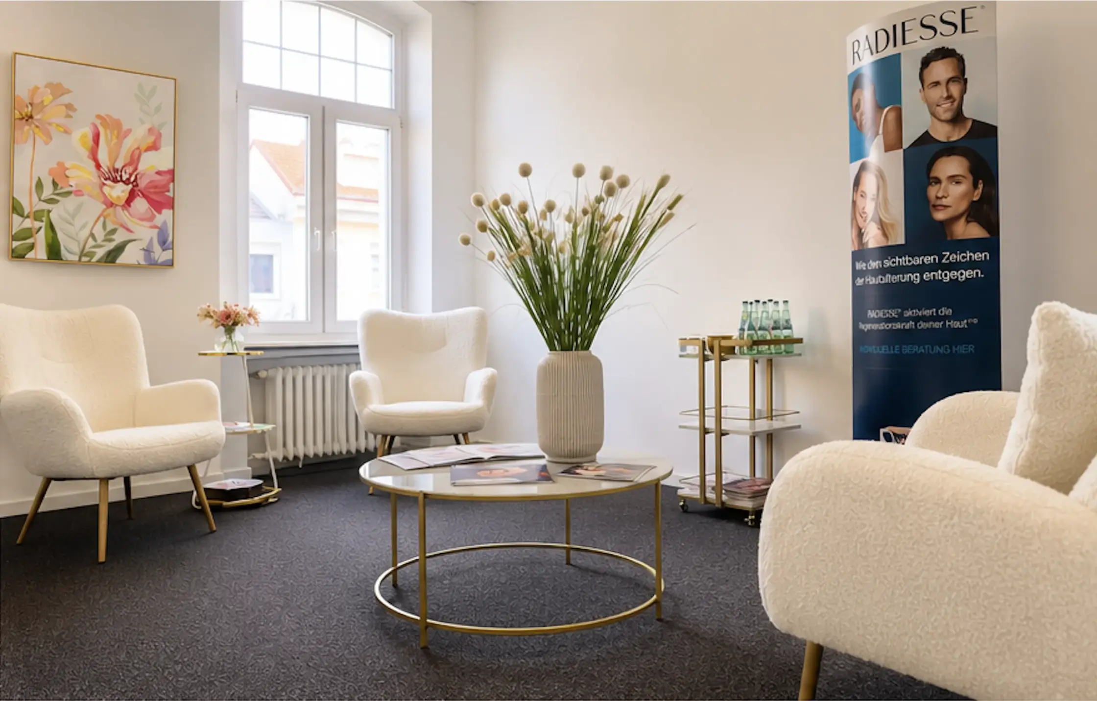 Wartebereich mit weißen Bouclé-Sesseln, goldenem Couchtisch und hohem Bogenfenster